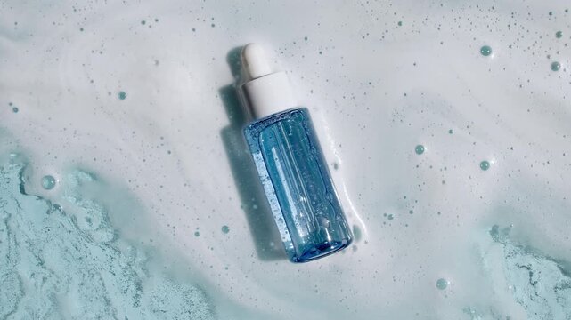 Bottle with a pipette for oil, toner, emulsion on water texture background surface with bubbles of white soapy foam. Women's cosmetics skincare, body care. Products advertisement spa, relaxation. 4k