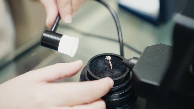 Gemologist inspecting diamond ring using microscope