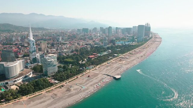Aerial view Batumi modern city skyline and beachfront with tall high rise towers, new construction sites and coastline along the Black Sea in Georgia