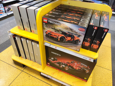 Rome, Italy - March 29, 2026: LEGO Technic Bugatti Chiron and Ferrari SF90 model kits displayed on a yellow shelf in a retail store