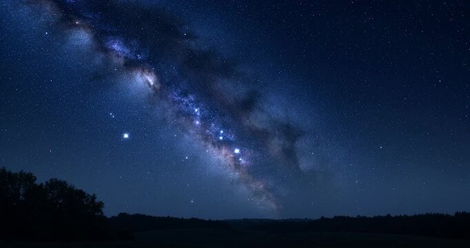 Milky way galaxy arching over dark rural landscape with starry sky and glowing core, silhouetted trees under starry night, bright Milky Way forming serene starscape across clear night sky