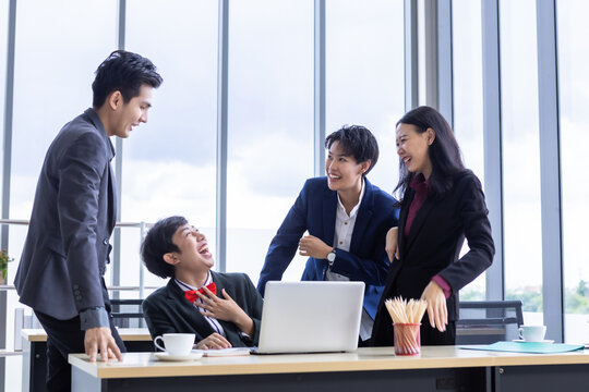 Successful happy workers Group of asian business people with diverse genders (LGBT) and congratulate to Homosexual businessman see a successful business plan on the laptop computer at office