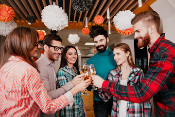 Obraz premium Young friends toasting at a cheerful office party with decorations and drinks, celebrating teamwork and friendship during a casual indoor team celebration