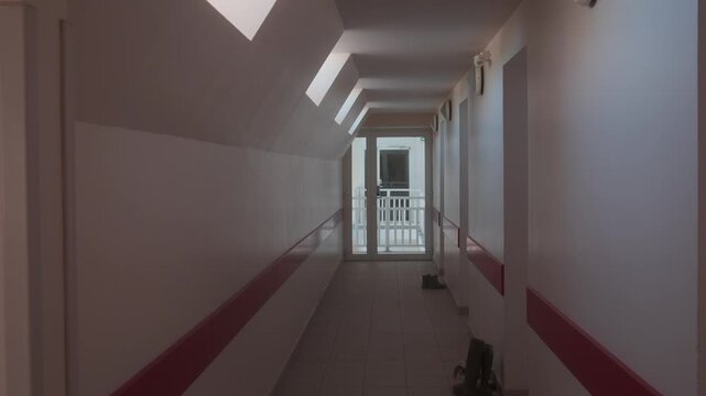 View of a quiet interior corridor with skylights and a glass door at the end in a residential building at Le Crotoy, France.