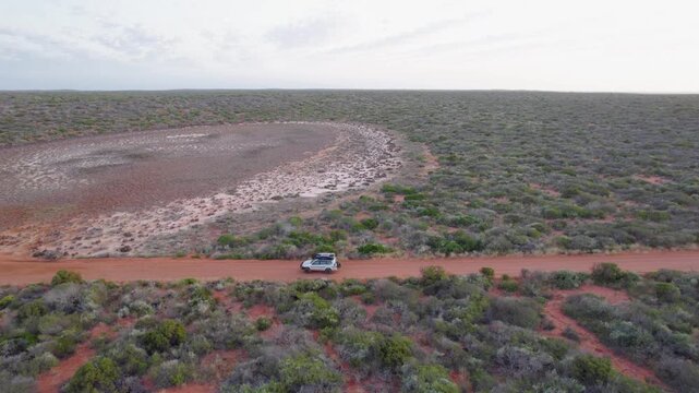4WD Adventure Truck Drives across Red Dirt Track in Francois Peron National Park, Remote Outback Landscape in Western Australia - Aerial Drone Shot