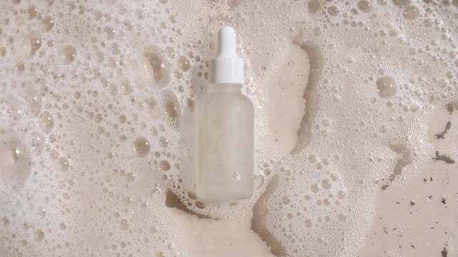 Bottle with a pipette for collagen serum, oil, toner on water texture background surface with bubbles of white soapy foam. Medical skin care. Packaging for design, advertising of a cosmetic product.4k