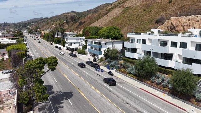 Cinematic daytime aerial drone footage captured just above the Pacific Coast Highway, featuring a smooth parallax pan moving toward the center of the roadway.
