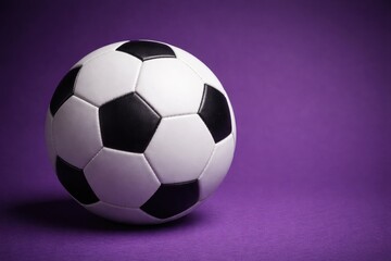 Naklejka premium Close up of a soccer ball positioned on a rich purple matte surface with copy space