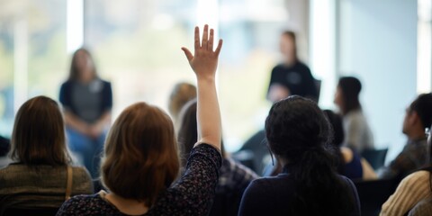 Obraz premium Participant raising hand to ask a question in sunlit seminar with presenters softly out of focus, modern corporate setting
