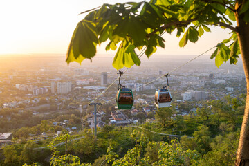 Cable car gondola over Almaty city at colorful sunset with cityscape © Ployker
