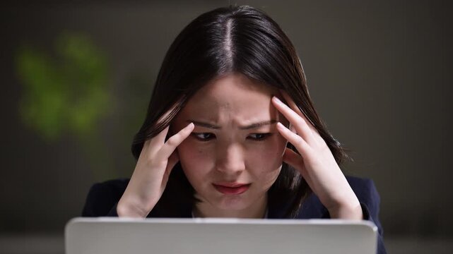 え、これってミスかな&hellip;？失敗して残業で仕事が終わらずにで頭を抱える悩む女性ネガティブビジネスシーン　転職やストレスと仕事の問題イメージのクローズアップ　目を動かしてメールを読む
