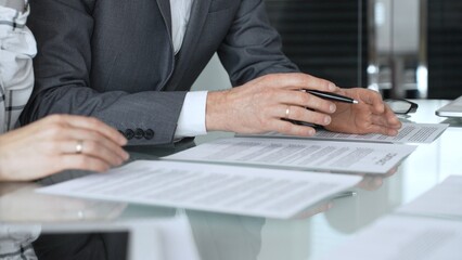 Fototapeta premium Business executive hands gesturing over contract on glass table during formal office meeting negotiating legal agreement terms. Business people concept