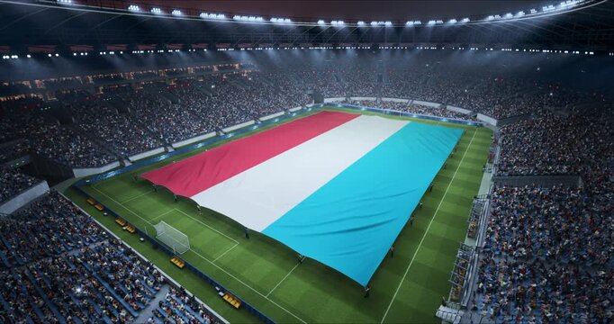 Professional Stadium Soccer Game Championship With Flag of Luxembourg Spread Across the Pitch Before Football Match Start. Cheering Crowds of Fans Surround the Field. Aerial Elevated Static Wide Shot