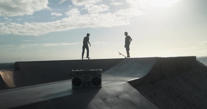 Young people having fun at skateboard park outdoor at sunset - Summer lifestyle, skater boys and extreme sport concept