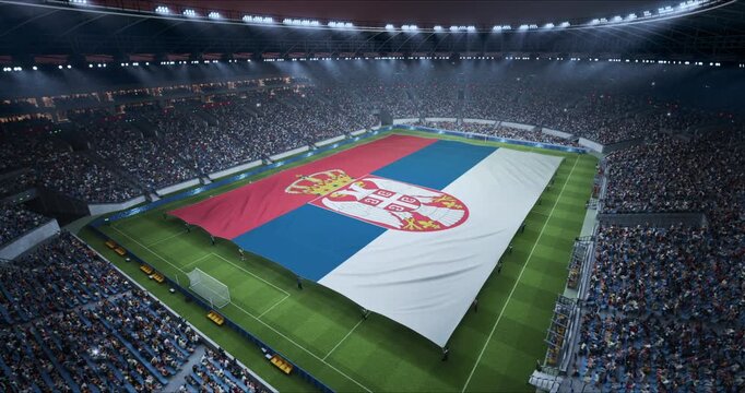Professional Stadium Soccer Game Championship With Flag of Serbia Spread Across the Pitch Before Football Match Start. Cheering Crowds of Fans Surround the Field. Aerial Elevated Static Wide Shot