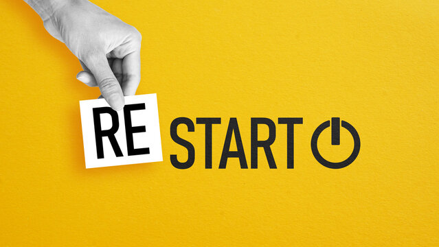 Restart concept with hand placing RE before start word, new beginning, motivation, change, fresh start, reset mindset and personal growth on yellow background with power symbol