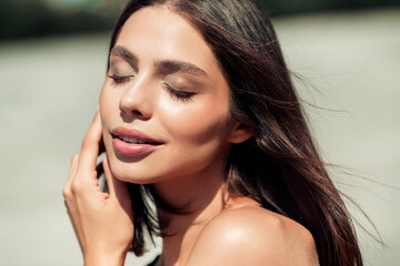 Young woman portrait with closed eyes enjoying sunlight, natural beauty and glowing skin outdoors © deagreez
