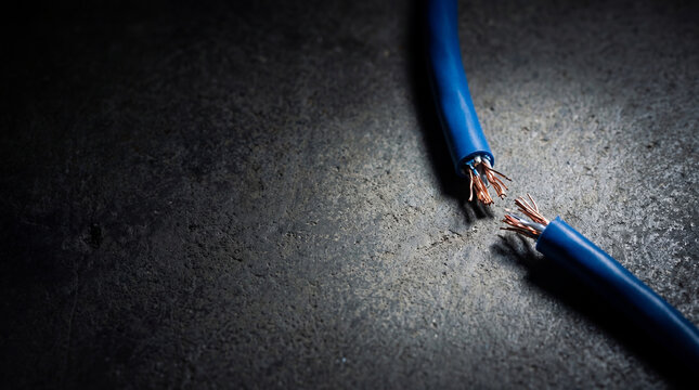 Cut blue internet cable on dark floor. Network disconnection and communication breakdown. Social media blocking and cyber security concept. Digital connection failure and internet censorship.