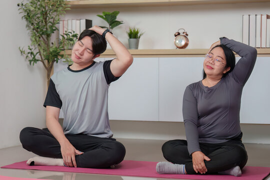 Asian man and woman stretching neck muscles at home, wellness