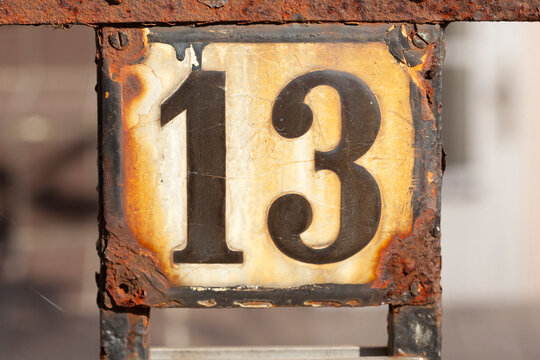 Hausnummernschild Nr. 13 an einem alten rostigen Gartenzaun, Deutschland