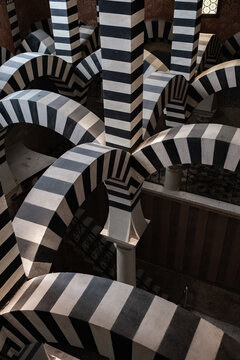 Bologna, Italy - 27 March 2022: View of the mesmerizing, black and white striped arches of Santo Stefano, a geometric dance of light and shadow creating a captivating visual rhythm.