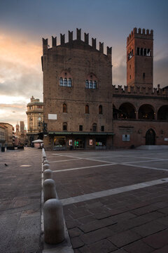 Bologna, Italy - 27 March 2022: View of Palazzo Re Enzo's weathered brick facade against the soft hues of the sunset sky, creating a scene of timeless beauty.