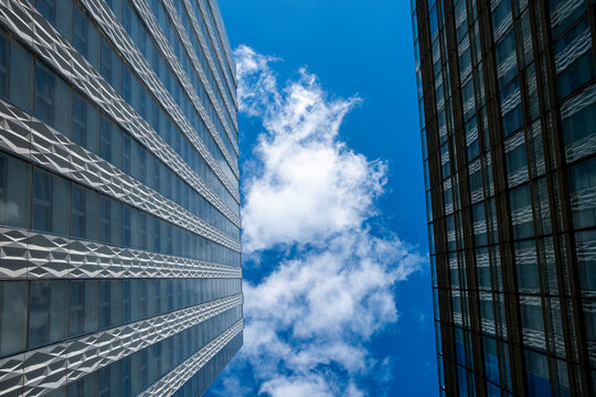 Clouds and sky over architecture skyscraper office tower with steep perspective looking up across Paris La Defense business quarter highrise