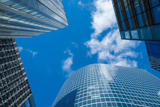 Glass skyline architecture skyscraper office beneath clouds with bold perspective looking up over France La Defense financial quarter towers