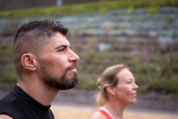Fototapeta premium Active couple standing outdoors, woman in foreground looking ahead with focus