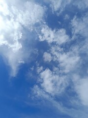 Obraz premium Blue sky filled with scattered fluffy and wispy white clouds. Bright daytime weather background