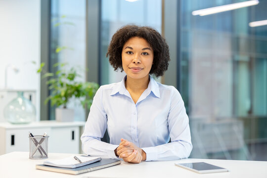 Portrait of a young African American woman sitting at an office desk and smiling at the camera