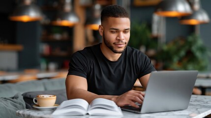 Obraz premium Black male student working on laptop in modern cafe with coffee