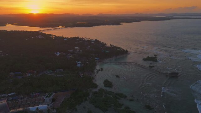 aerial dramatic sunset view of waves crashing over the reef at Cloud 9, Siargao. Drone footage of the famous surf break and clear tropical waters in General Luna, Philippine islands
