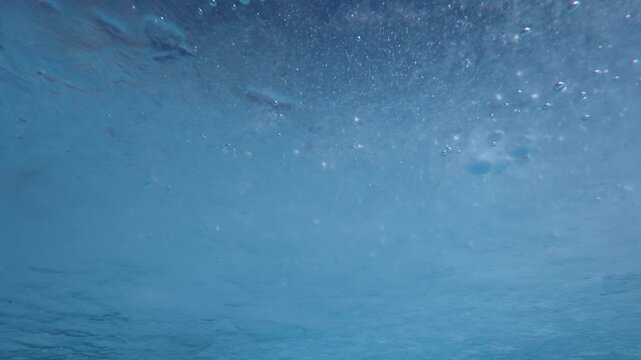 Thin melting spring translucent ice with frozen air bubbles drifting with the current, underwater view of spring ice drift, close-up, natural background