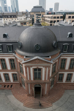 Frankfurt am Main, Germany - 10 April 2017: View of the historic Goethe House, its dark dome and reddish baroque facade standing majestically against a backdrop of modern skyscrapers.