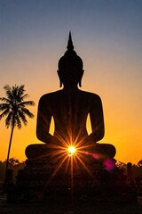 Obraz premium Silhouette of Buddha meditating in lotus pose with bright sun rising behind creating a starburst effect and palm tree