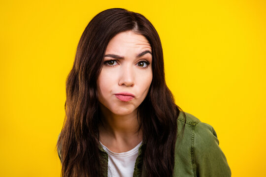Young woman with skeptical confused expression and raised eyebrow in a bright yellow studio portrait conveying doubt and curiosity