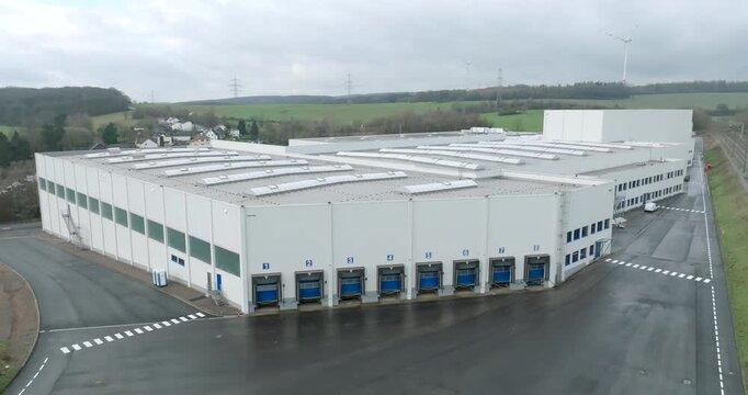 Aerial wide shot of a modern distribution center with a row of blue loading docks and white facade