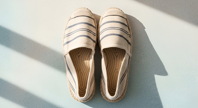 Striped espadrilles with dramatic shadows, summer fashion canvas shoes, nautical style footwear for beach vacation, minimalist flat lay top view, sunny holiday atmosphere.