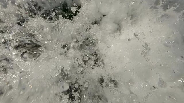 Extreme closeup of splashing and water droplets in a turbulent stream, super slow motion. 