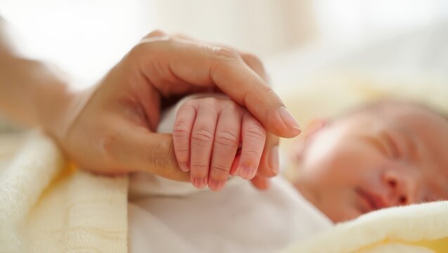 A heartwarming scene of a parent cradling a newborn baby's hand, conveying love, care, and a deep connection between generations.