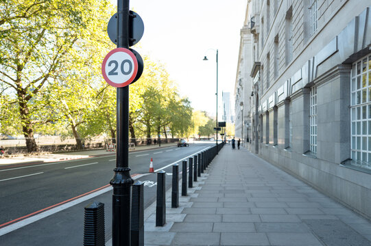 Shallow focus of a typical 20 mph speed sign located within the central London district of Millbank. The river thames is to the left and a large, government building to the right.