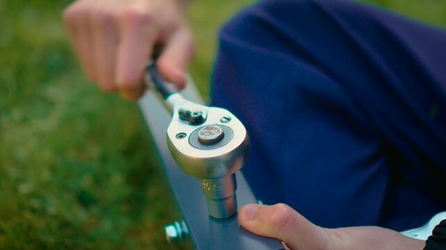 Macro tightening with ratchet wrench on gray steel beam during outdoor assembly. Precise fastening action with socket tool and metal hardware in natural light. DIY construction concept with worker
