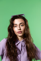 Fototapeta premium Stylish young woman poses confidently against a vibrant green backdrop in modern fashion