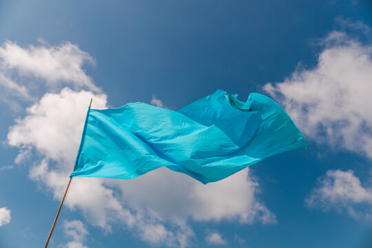 Blue warning flag fluttering in wind against sky with clouds on tropical beach
