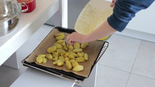 Preparing seasoned potato wedges for baking on a parchment-lined baking sheet
