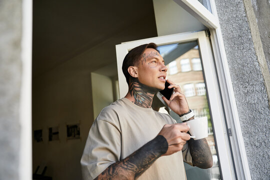 Charming young man enjoys a moment of blissful solitude at home while talking on the phone