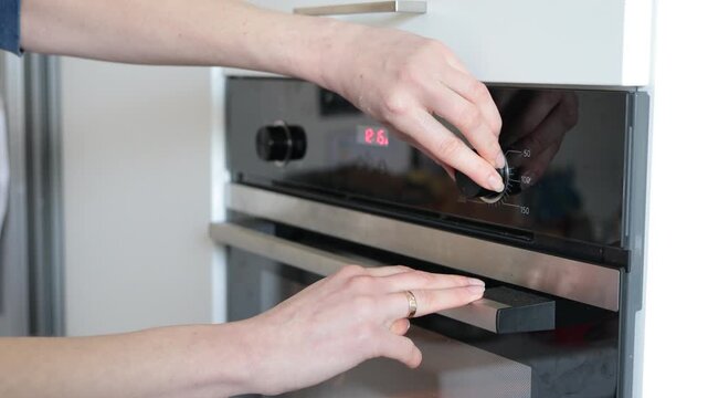 Close-up of hands adjusting modern oven controls for cooking preparation
