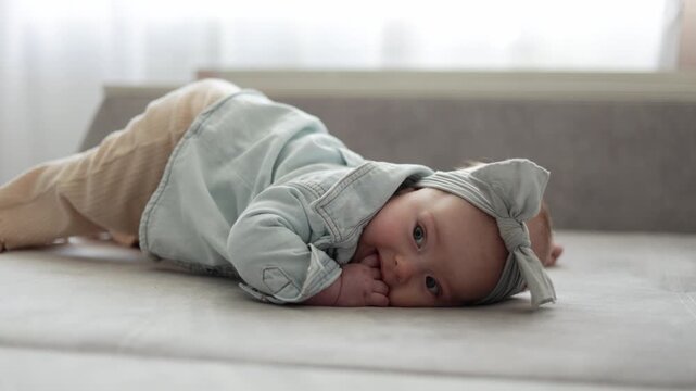 Adorable baby girl in denim shirt and headband explores her surroundings