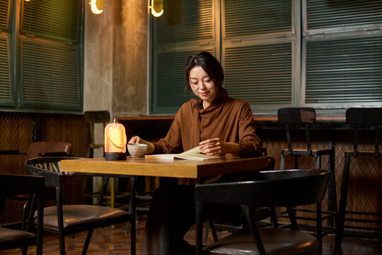 A woman enjoys a cup of tea and a good book at a serene tea house